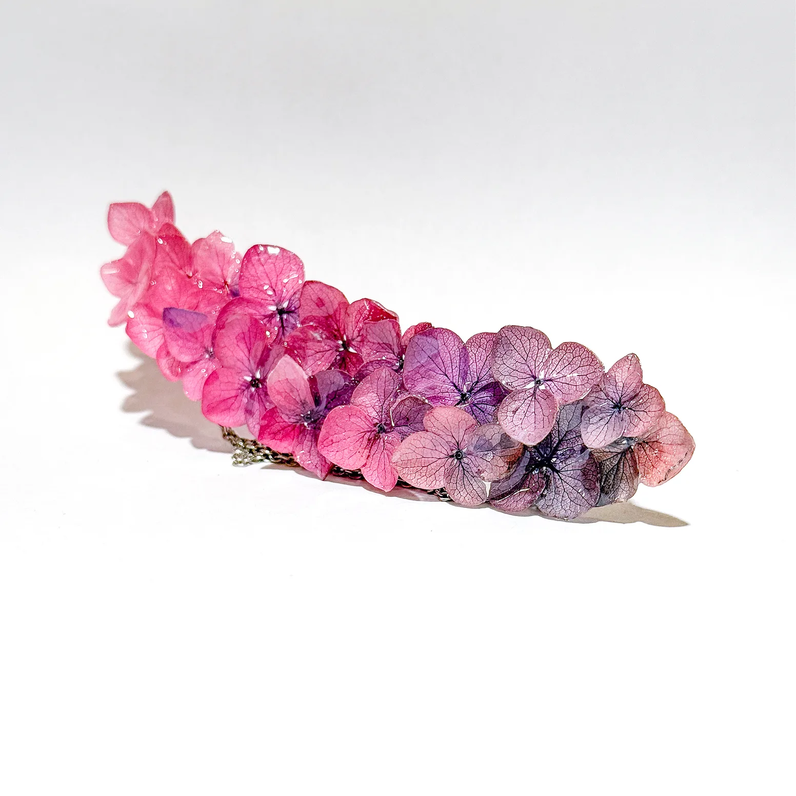 Collana di ortensie rosa e lilla su fondo bianco